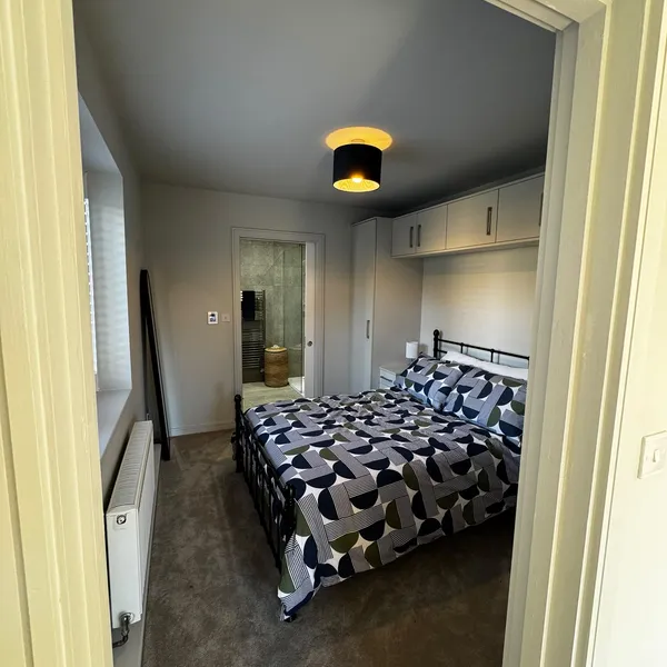 Annex bedroom seen from the doorway, with overhead cupboards around the bed and the wet room door beyond