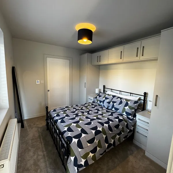 Bedroom with a run of fitted overhead cupboards and wardrobes around a double bed