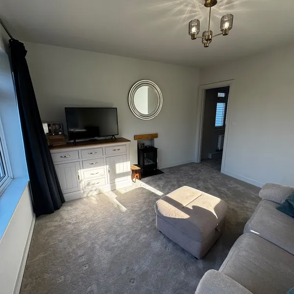Annex living room with a sofa, a wood-burning stove and a door through to the rest of the annex