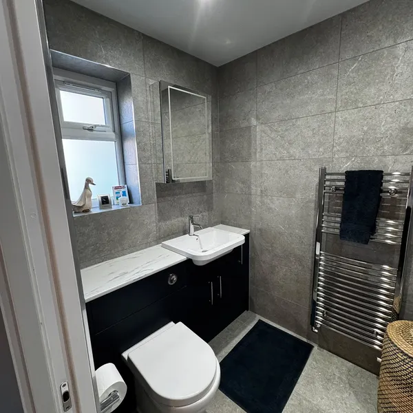 The wet room seen from its wide doorway, with the WC, vanity unit and a chrome heated towel rail