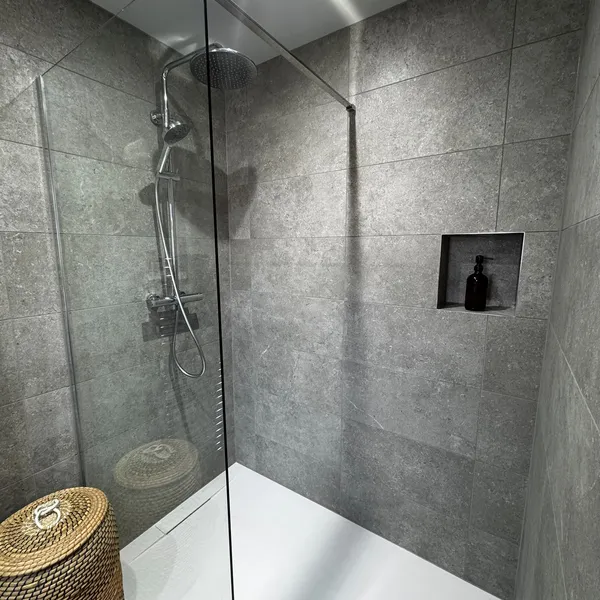 Level-access wet room in a Horsham annex, with a zero-step shower behind a glass screen and a recessed niche