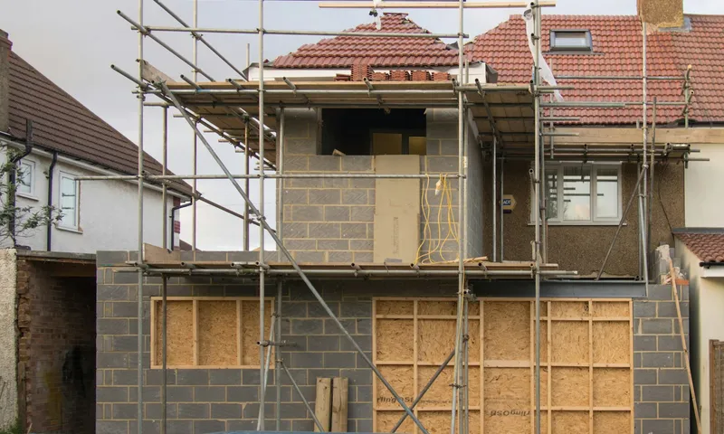 House extension under construction, wrapped in scaffolding