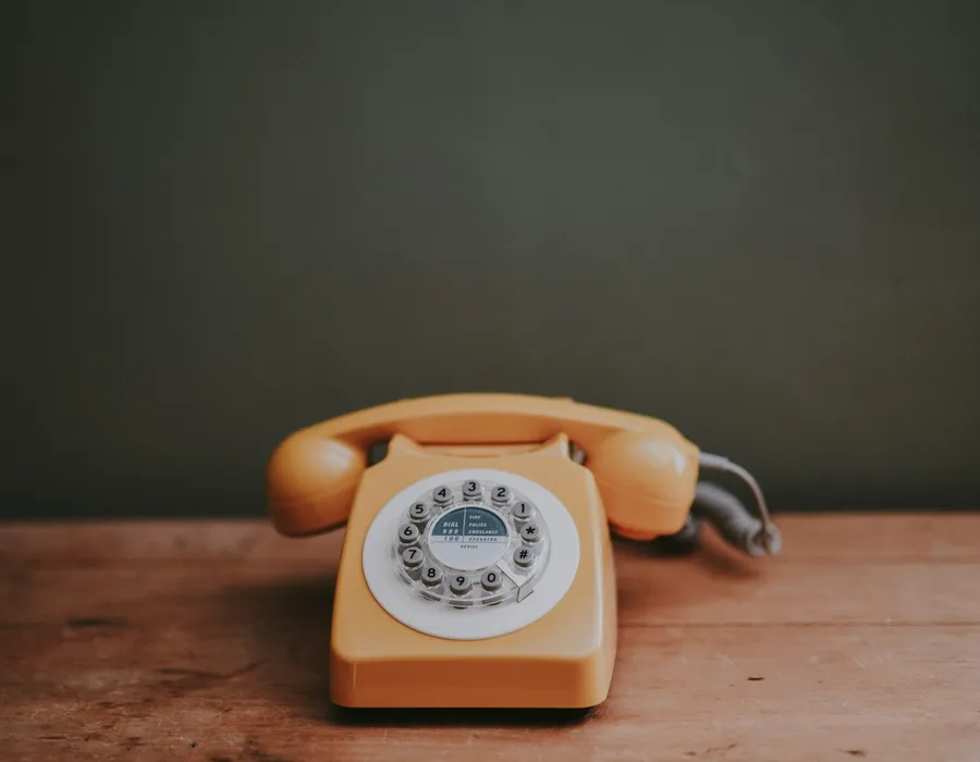 Cream rotary dial telephone on a wooden surface