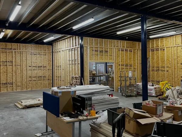 New rooms under the mezzanine sheathed in OSB, with a doorway formed through to the corridor beyond