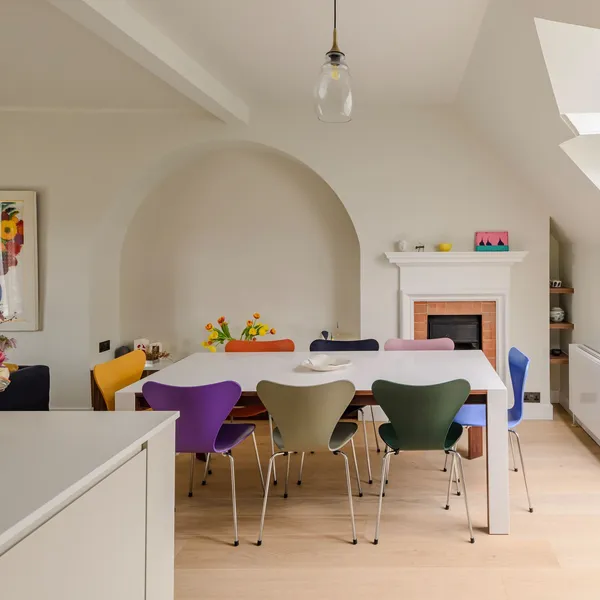 Dining table in front of an arched alcove and fireplace, with the end of the kitchen island in the foreground