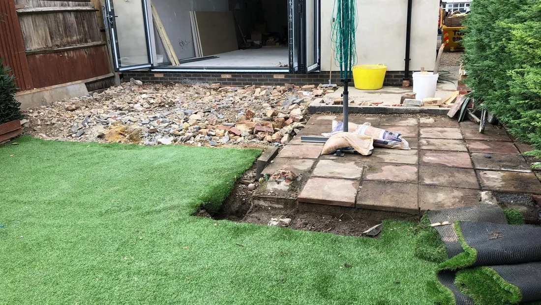 A single-storey rear extension mid-build, with the bifold doors in and the old patio being lifted in front of it