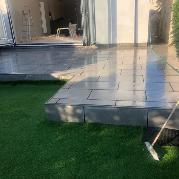 New grey paving laid as a raised terrace outside the bifold doors, with a step down to the lawn