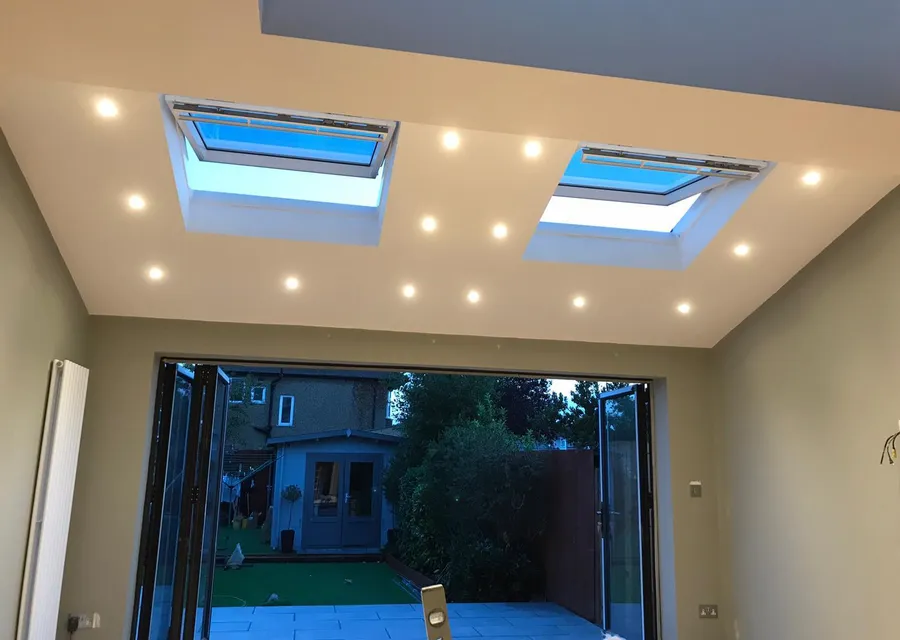 Inside a finished single-storey rear extension, with two opening rooflights and recessed downlights in the ceiling and bifold doors open to the garden