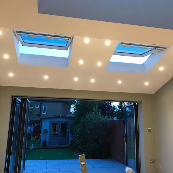 Inside the finished extension, with two rooflights and recessed downlights in the ceiling and bifold doors open to the garden