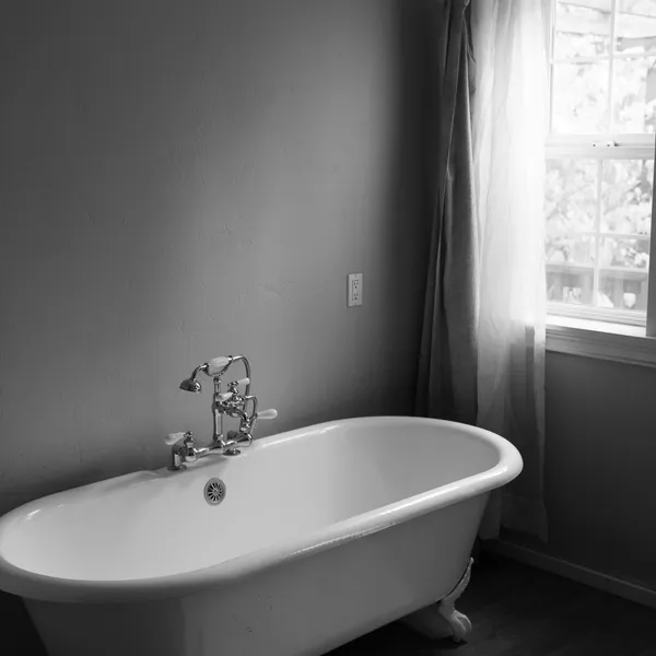 Freestanding roll-top bath beside a window