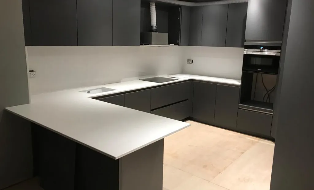 Bespoke charcoal handleless kitchen with a white worktop and breakfast bar, in the final stages of fitting