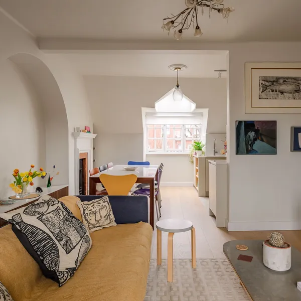 Open-plan living room with a mustard sofa and leather armchairs, looking through to the dining table and an arched alcove