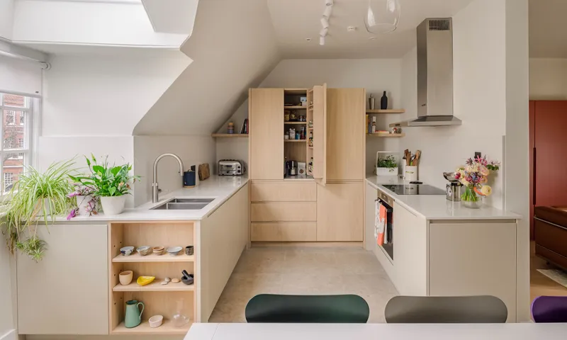 Oak kitchen fitted under a sloping loft ceiling, with the larder cupboard open beside the hob